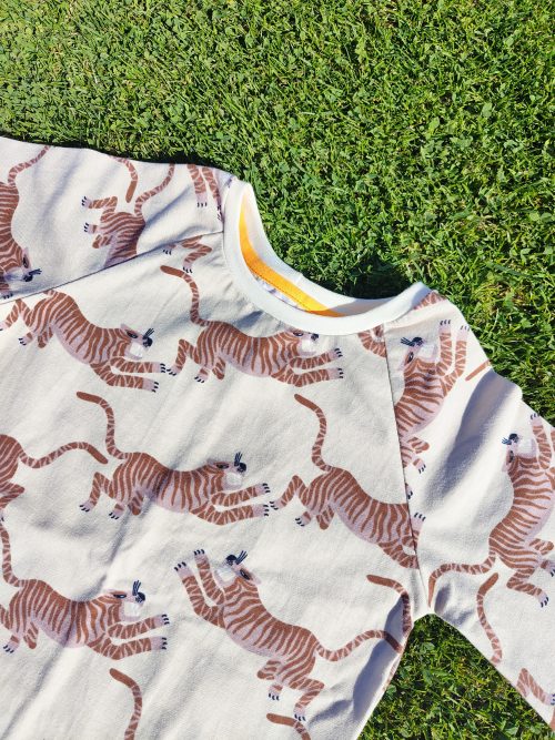 T-shirt manches courtes raglan tiger tales avec un motif tigre japonisant couleur ocre sur fond beige. On aperçoit le col en bord côte GOTS et la bande de propreté qui apportent une finition impeccable au t-shirt