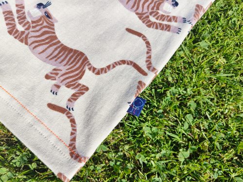 T-shirt manches courtes raglan tiger tales avec un motif tigre japonisant couleur ocre sur fond beige. Mise en valeur de l'étiquette extérieure qui porte le logo de Chiche ! Un bonhomme dessiné par la fille de 3 ans de la créatrice