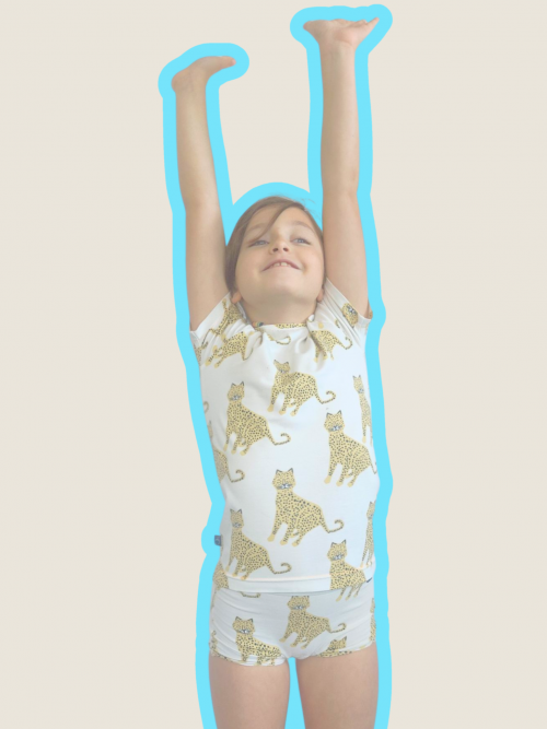 Image de notre ensemble Chiche : Une fillette joyeuse portant un ensemble boxer et t-shirt manches courtes pour filles au motif léopard sur fond écran et un boxer assorti.